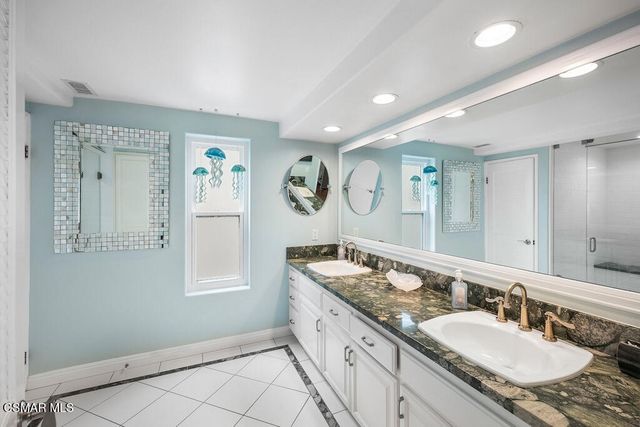 a bathroom with double vanity sinks a mirror and a shower