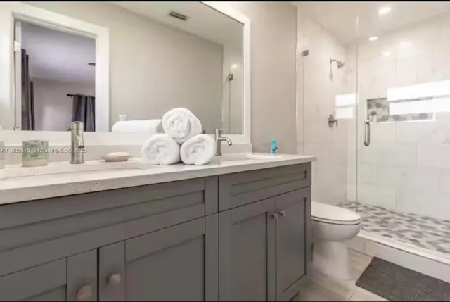 a bathroom with a sink a toilet and a large mirror