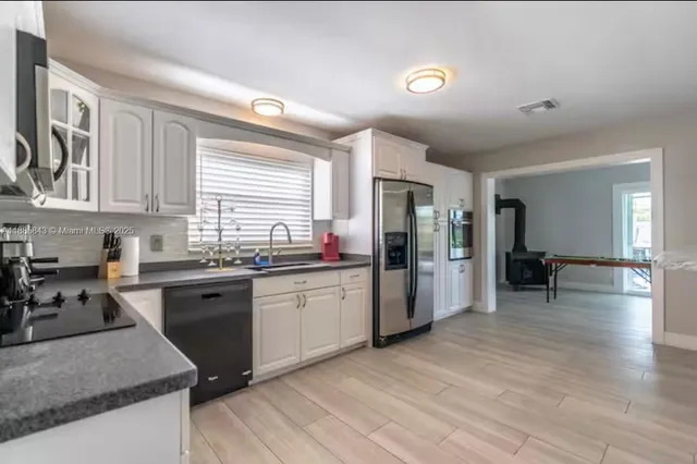 a kitchen with stainless steel appliances granite countertop a stove a sink dishwasher and a refrigerator with wooden floor