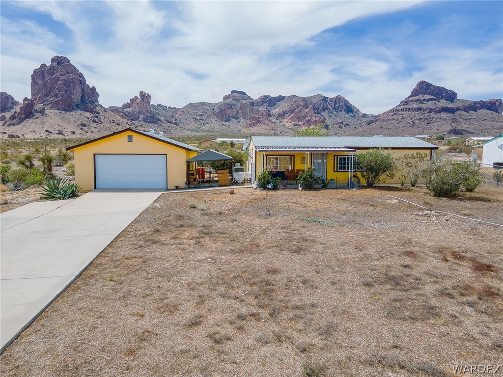 2465 Egar Road Golden Valley, AZ 86413 - Photo 63 of 98 The property features a yellow exterior and a concrete driveway leading to a garage with a white door