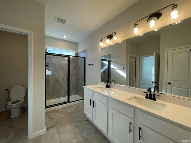 a spacious bathroom with a double vanity sink toilet and a mirror