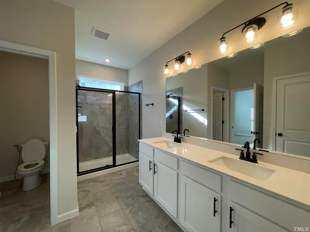a spacious bathroom with a double vanity sink toilet and shower