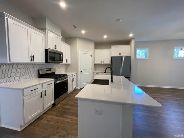 a kitchen with granite countertop a stove top oven a sink dishwasher and a refrigerator with wooden floor