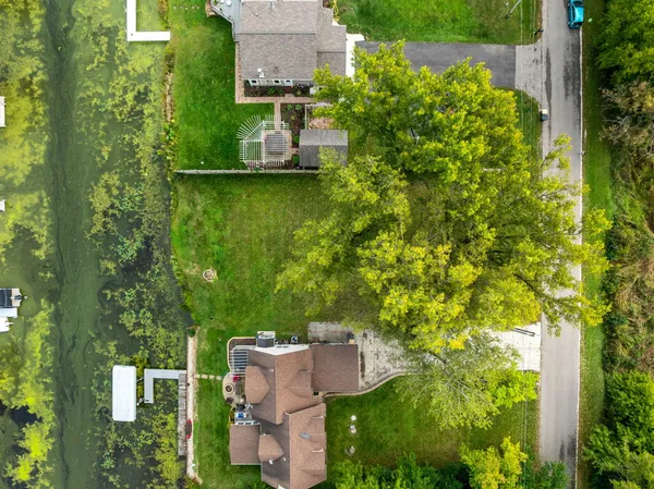 an aerial view of a house with a yard lake and trees all around