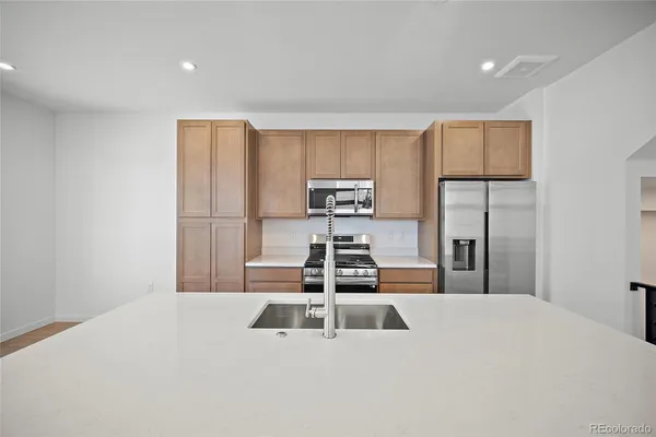 a kitchen with a refrigerator a stove top oven and wooden floor