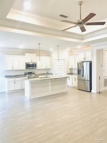 a large white kitchen with cabinets a sink and a stove