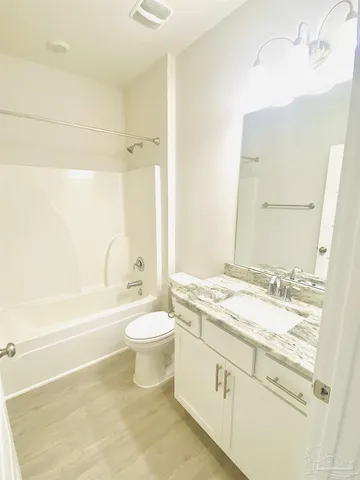 a bathroom with a granite countertop sink toilet a large mirror a bathtub and shower