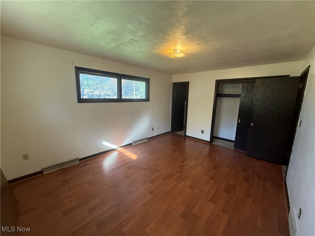 683 Robinson Road Campbell, OH 44405 - Photo 17 of 23 Unfurnished bedroom with dark wood finished floors, multiple closets, and a textured ceiling