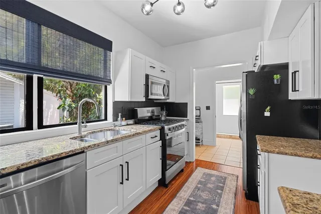 a kitchen with granite countertop a sink stove and refrigerator