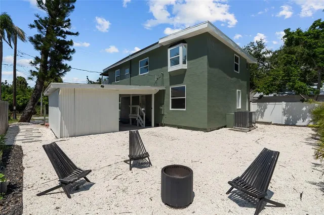 a backyard of a house with table and chairs and potted plants