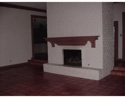a view of an empty room with wooden floor and a fireplace