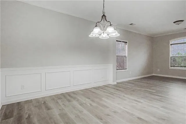 a view of empty room with wooden floor and chandelier