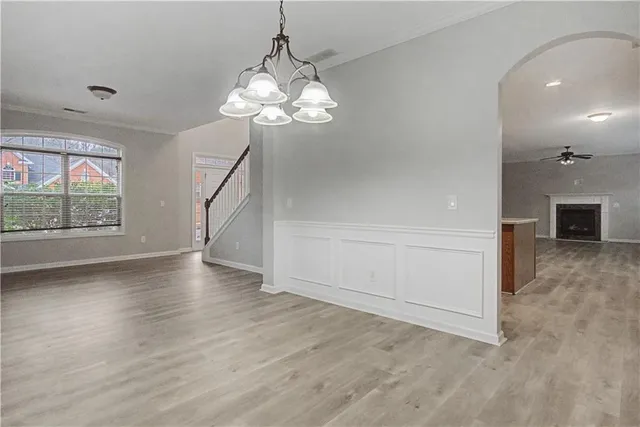 an empty room with wooden floor chandelier and windows