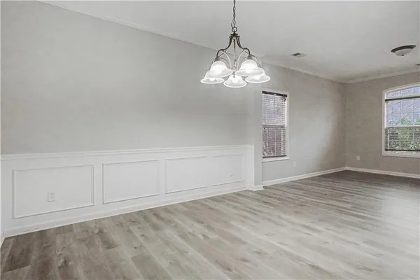 a view of empty room with wooden floor and chandelier