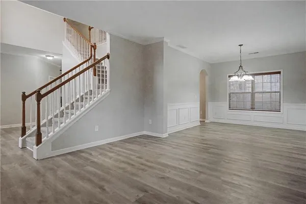 a view of an empty room with wooden floor and pendant lights