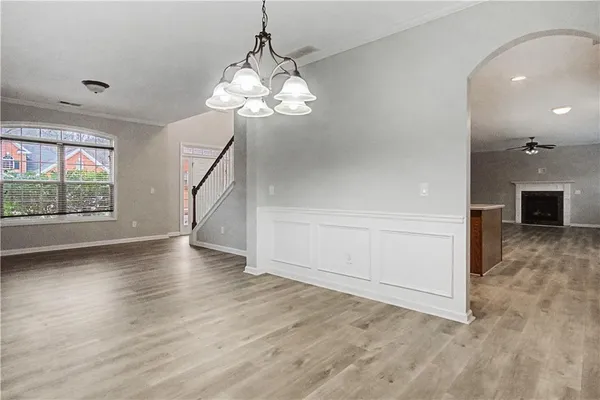 an empty room with wooden floor chandelier and windows