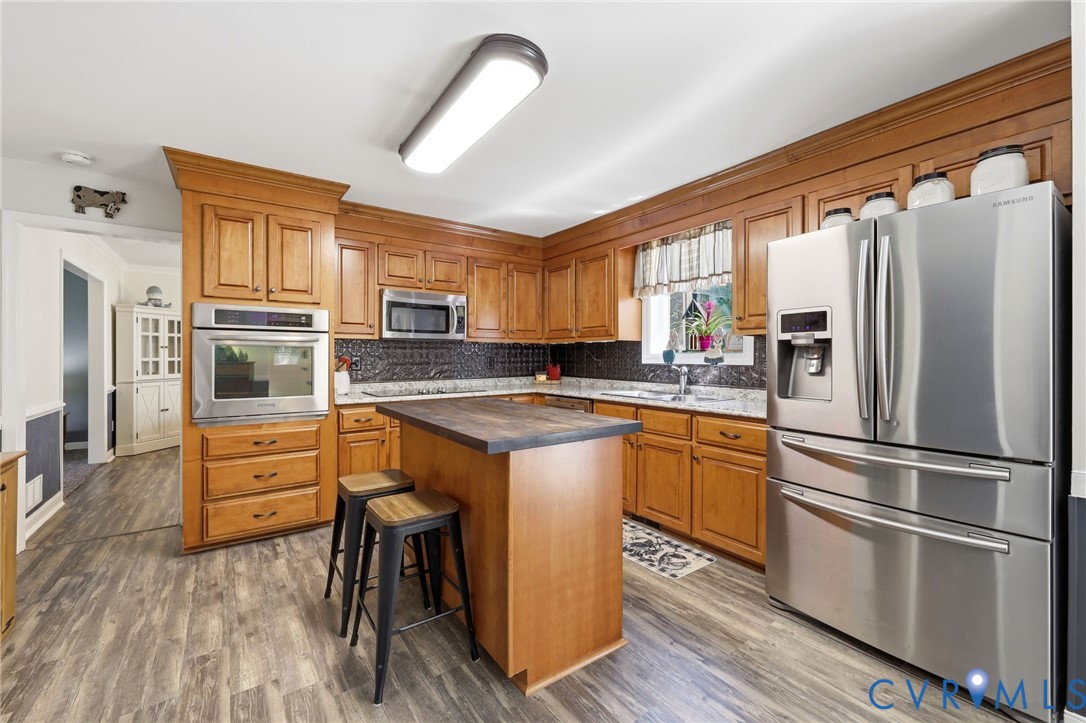 11200 Surry Road Chester, VA 23831 - Photo 16 of 48 a kitchen with stainless steel appliances granite countertop a refrigerator a stove and a sink with cabinets