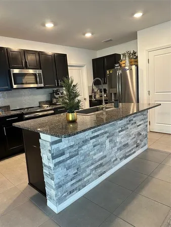 a kitchen with stainless steel appliances granite countertop a stove a sink and a microwave