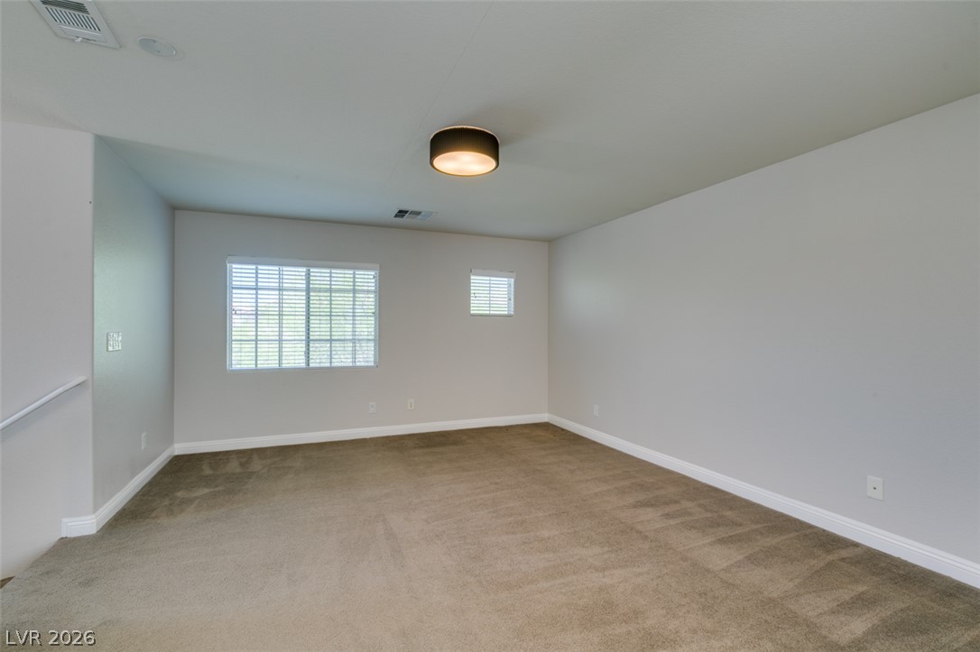 8909 Houston Ridge Avenue Las Vegas, NV 89178 - Photo 23 of 45 A spacious, naturally illuminated room boasts plush carpet flooring and clean, minimalist design.