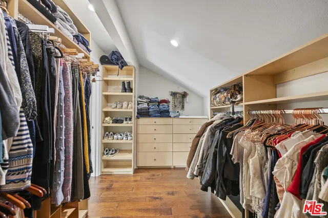 a view of walk in closet with clothes and shoes