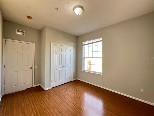 an empty room with wooden floor and windows