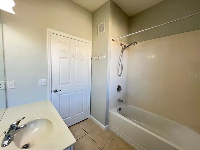 a bathroom with a tub shower sink and vanity