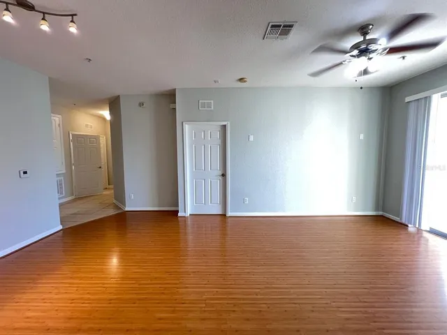 a view of an empty room with window and wooden floor
