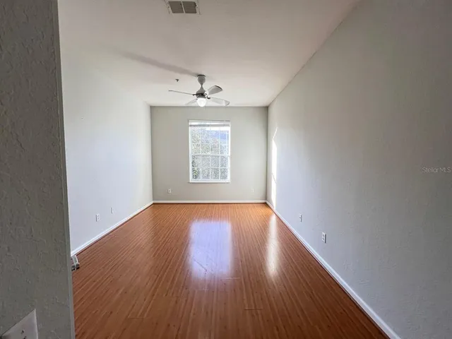 an empty room with wooden floor chandelier and windows