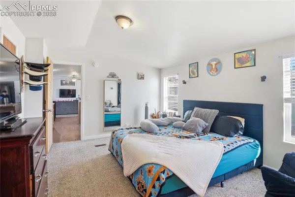 a bedroom with a bed mirror and a kitchen