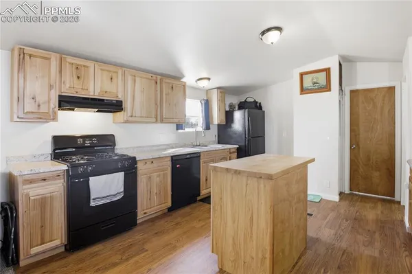 a kitchen with stainless steel appliances granite countertop a stove top oven a refrigerator a sink and dishwasher with wooden floor