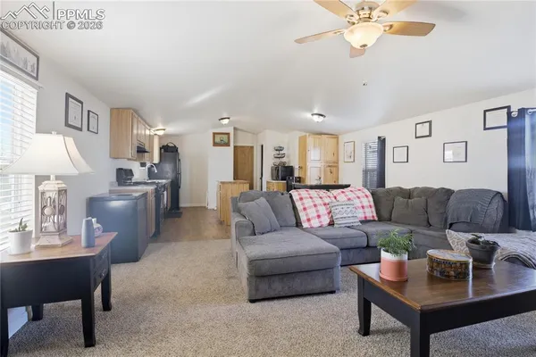 a living room with furniture kitchen view and a chandelier