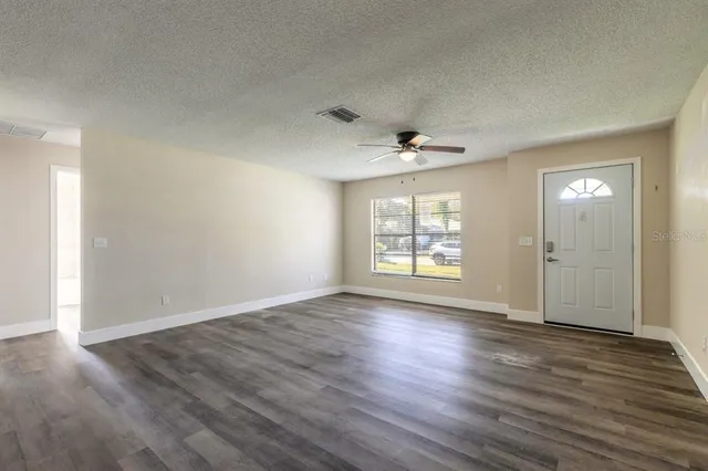 a view of an empty room with wooden floor and a window
