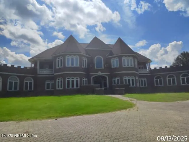 a view of a brick house next to a yard with big trees