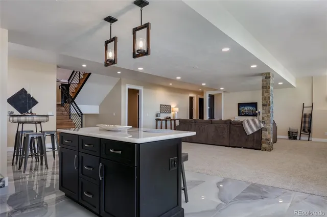 a living room with stainless steel appliances kitchen island granite countertop a sink and a large mirror