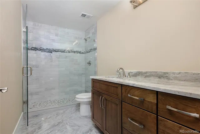 a bathroom with a granite countertop sink a toilet and shower