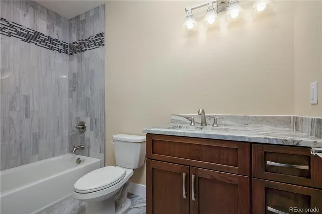 a bathroom with a granite countertop sink toilet and shower