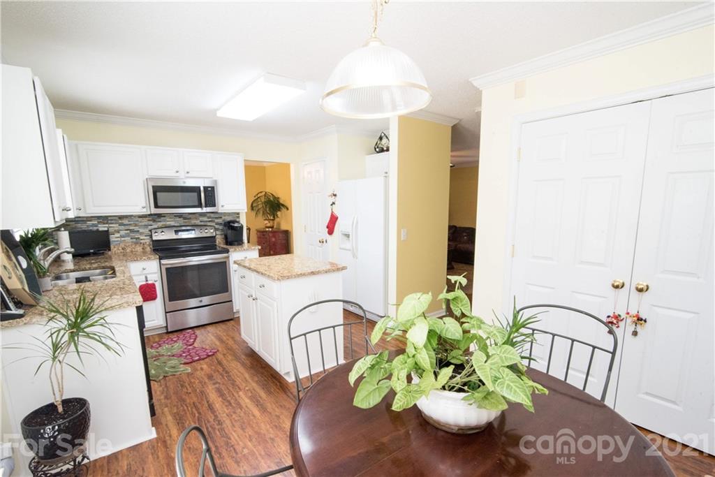 11427 Gold Pan Road Charlotte, NC 28215 - Photo 11 of 34 a kitchen with stainless steel appliances a white table a stove a microwave a refrigerator and a window