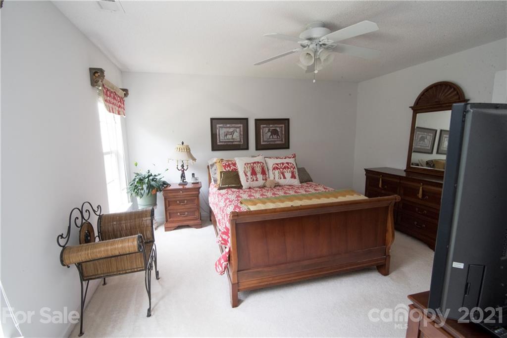 11427 Gold Pan Road Charlotte, NC 28215 - Photo 21 of 34 a bedroom with a bed and a chandelier