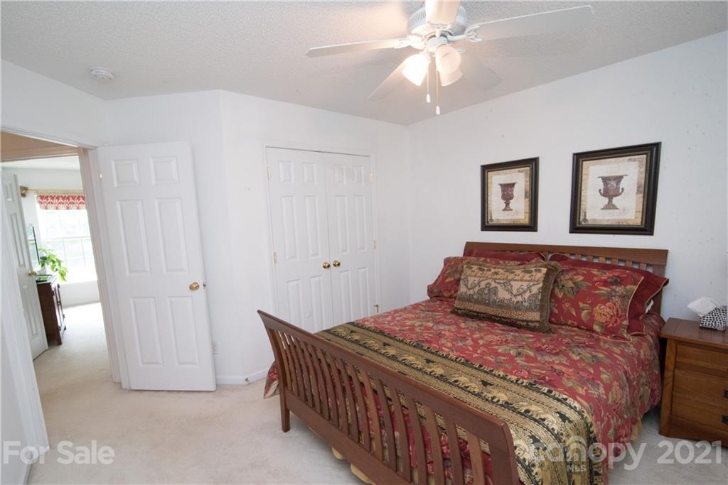 11427 Gold Pan Road Charlotte, NC 28215 - Photo 22 of 34 a bedroom with a large bed and a chandelier