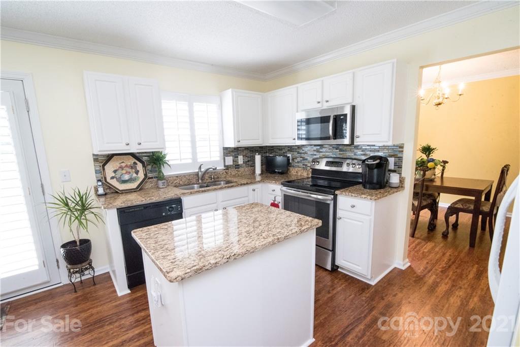 11427 Gold Pan Road Charlotte, NC 28215 - Photo 10 of 34 a kitchen with a stove a sink a microwave a dining table and chairs