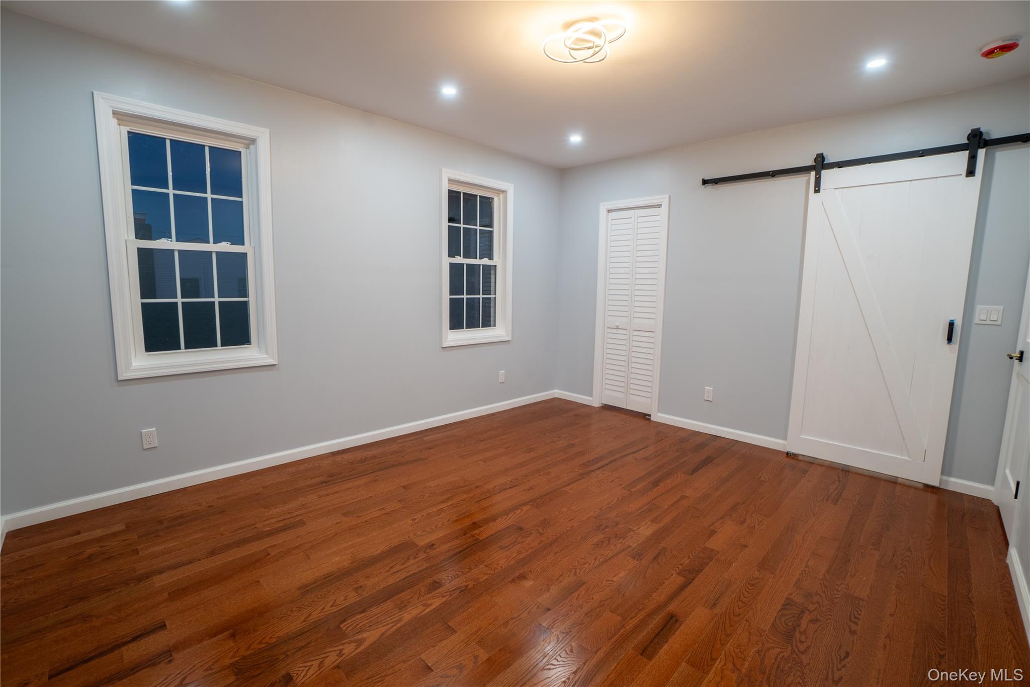 139 Maple Avenue Bethpage, NY 11714 - Photo 11 of 25 Unfurnished bedroom featuring wood finished floors, a barn door, and recessed lighting