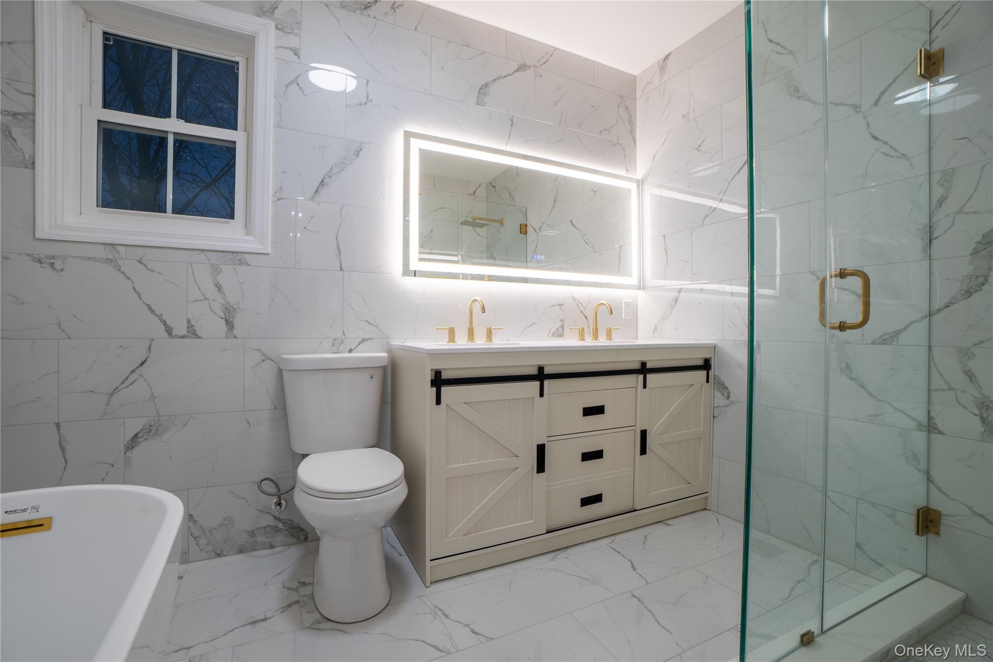 139 Maple Avenue Bethpage, NY 11714 - Photo 13 of 25 Bathroom with double vanity, light marble finish floors, a soaking tub, a marble finish shower, and tile walls