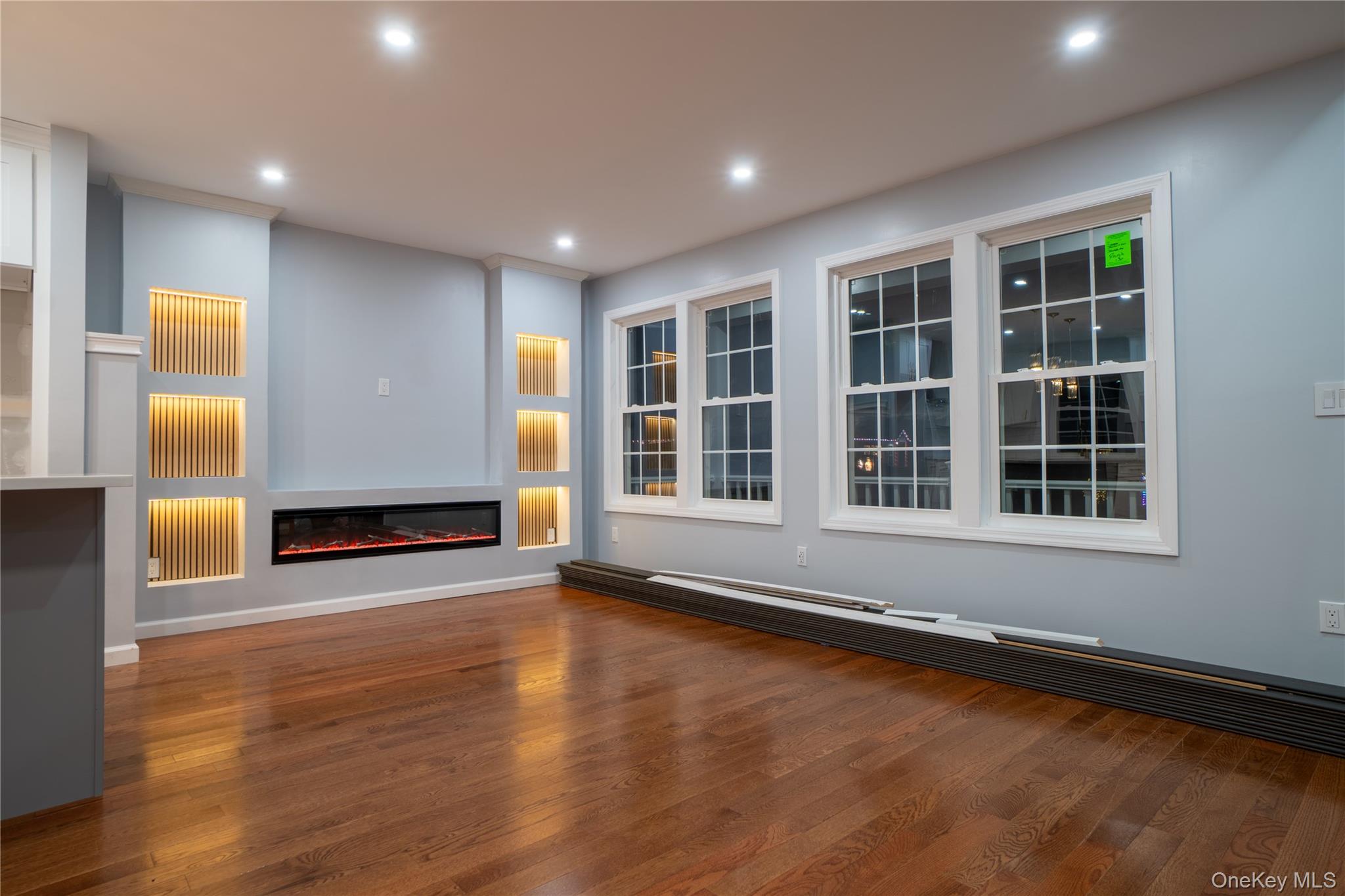 139 Maple Avenue Bethpage, NY 11714 - Photo 4 of 25 Unfurnished living room with a glass covered fireplace, dark wood-type flooring, recessed lighting, and a baseboard heating unit