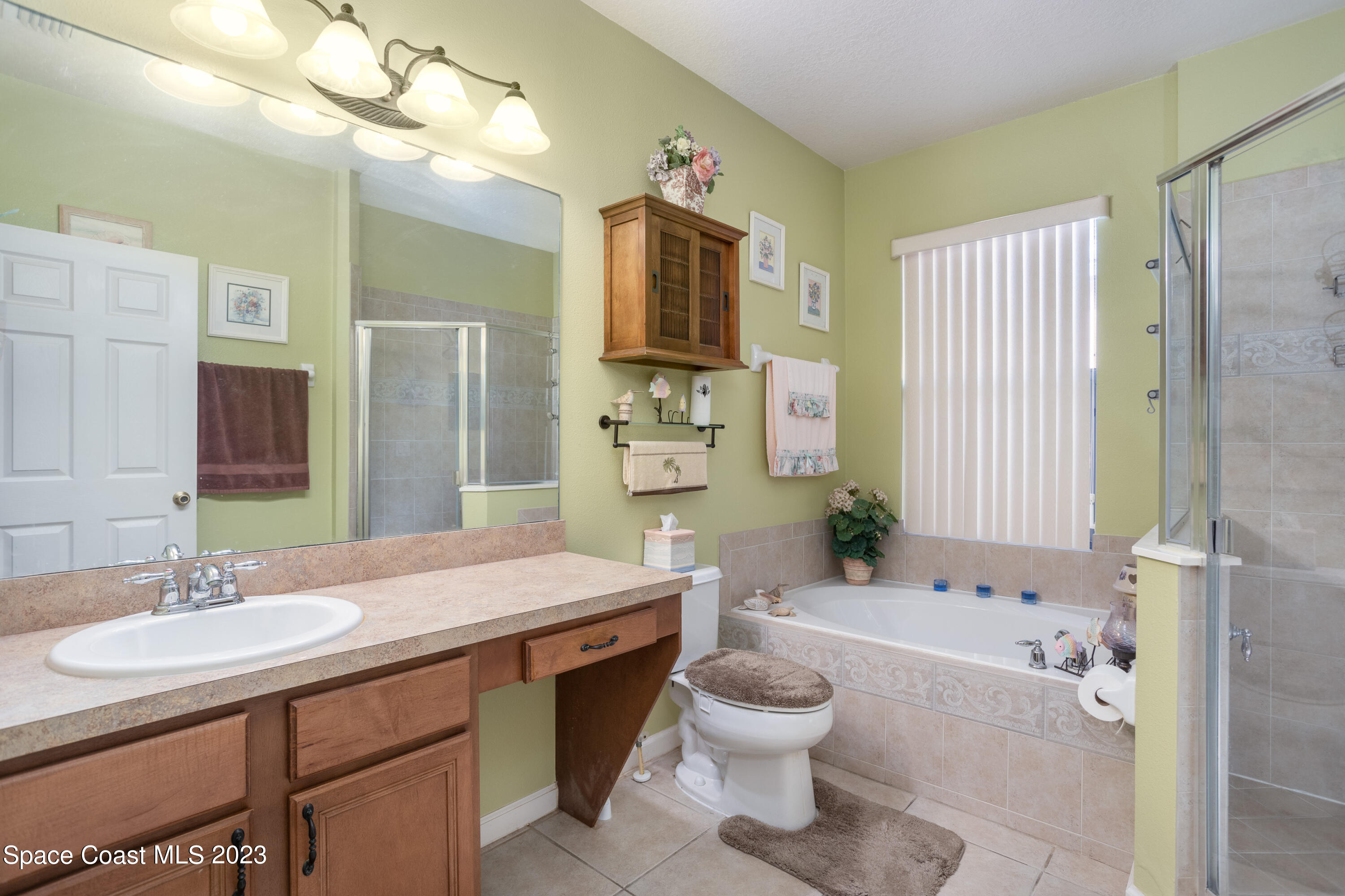4130 Millicent Circle Melbourne, FL 32901 - Photo 18 of 28 a bathroom with a granite countertop sink toilet a mirror a bathtub and shower