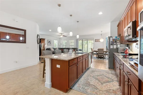 a kitchen with stainless steel appliances granite countertop a stove top oven a sink a dining table and chairs with wooden floor