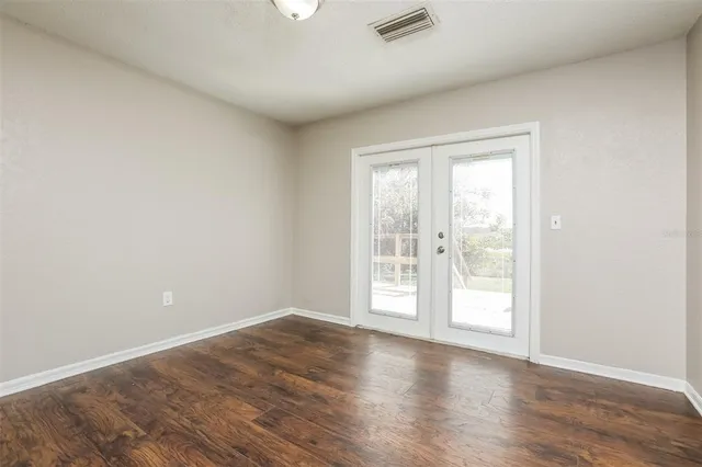 an empty room with wooden floor and windows