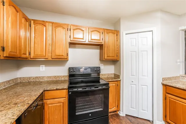 a kitchen with granite countertop wooden cabinets and a stove top oven