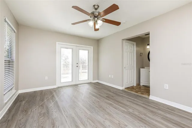 a view of an empty room with window and wooden floor
