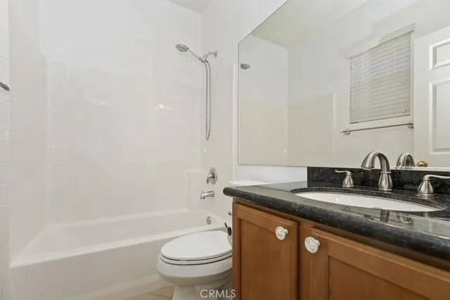 a bathroom with a granite countertop sink a toilet and bathtub