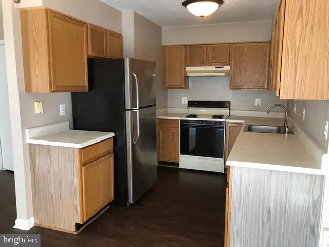 a kitchen with a refrigerator sink and wooden cabinets